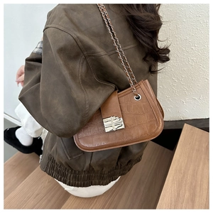 Brown crocodile pattern shoulder bag with silver buckle worn by a model in lifestyle setting