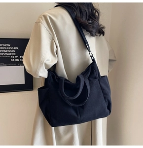 Detail of black corduroy crossbody tote bag showing vertical texture and adjustable strap