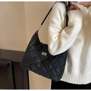 Detail of black quilted shoulder bag featuring a silver turn-lock and soft wrinkled texture