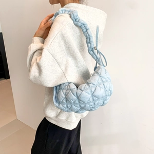 Light blue quilted crescent shoulder bag with braided strap worn by a female model