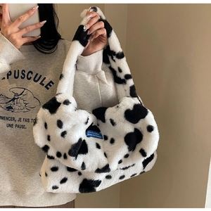 Detail of soft plush tote bag with black and white cow print texture and wide strap