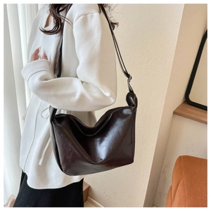 Deep brown PU leather crossbody bag shown on a model in a minimalist home setting