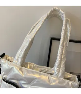 Detail of white quilted tote bag featuring smooth padded shoulder straps and zipper