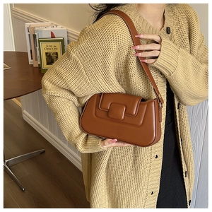 Detail of a brown leather shoulder bag featuring a vintage square flap and smooth finish