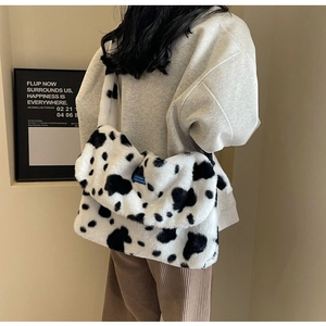 Detailed close-up of cow print plush handbag featuring soft faux fur texture and side blue tag