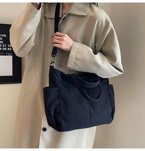 Detailed view of black corduroy tote bag worn with a stylish khaki trench coat