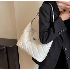 Detailed close-up of white quilted PU leather shoulder bag with silver turn-lock clasp