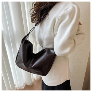 Detail view of smooth dark brown PU leather hobo bag with silver metal buckles