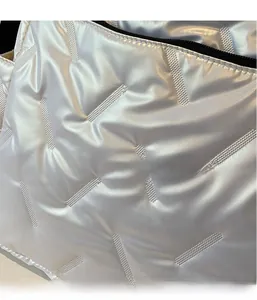 Close-up of quilted metallic silver fabric texture and black zipper detail on the shoulder bag