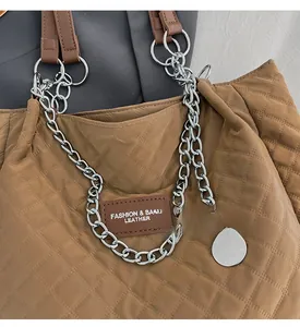 Détail du sac matelassé en nylon marron avec grosse chaîne argentée et écusson logo