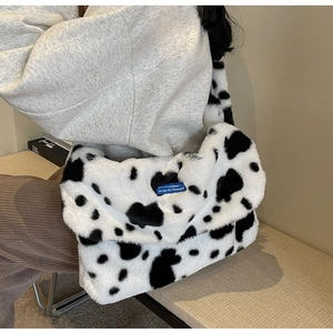 Close-up of a plush cow print shoulder bag showing soft texture and blue brand label