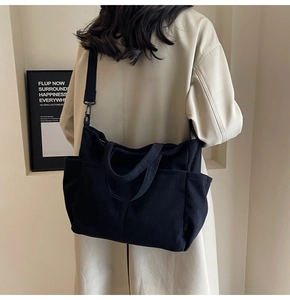 Detail of black corduroy tote bag with adjustable shoulder strap worn with beige trench coat