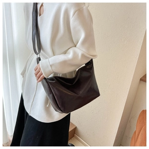Detail view of a dark brown half-moon crossbody bag in premium PU leather with shoulder strap