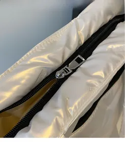 Detailed macro view of the glossy metal zipper puller on the white crossbody bag