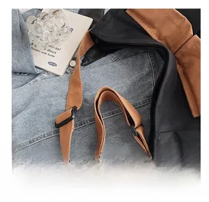 Detail of adjustable caramel canvas shoulder strap with buckle on a black crossbody bag