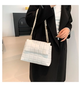 Détail d'un sac bandoulière matelassé blanc avec bandoulière en chaîne dorée tressée