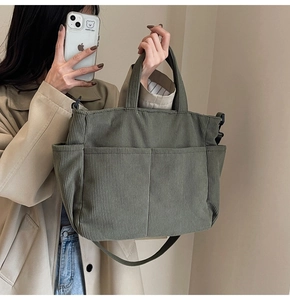 Detail of green corduroy tote bag with multiple front pockets and crossbody strap