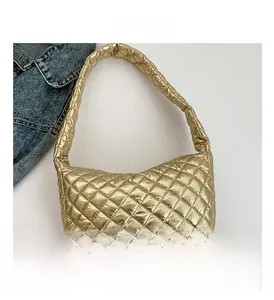 Detailed view of golden metallic quilted dumpling bag with wide shoulder strap design