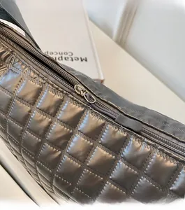 Detailed macro view showing the smooth metal zipper and quilted texture of the grey bag