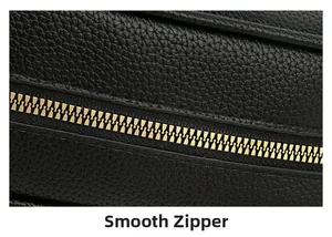 Close-up of black litchi grain leather texture and smooth golden metal zipper detail