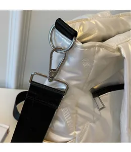 Detailed close-up of iridescent quilted bag with silver metal hooks and black strap