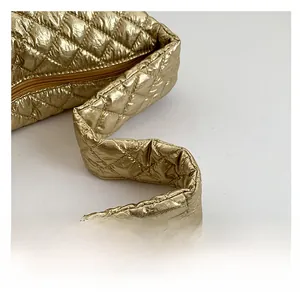 Detail of the shiny gold quilted dumpling bag with wide handle and metallic finish