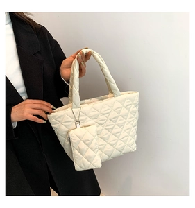 Detail shot of a winter cream quilted handbag featuring a mini pouch and puffer handle