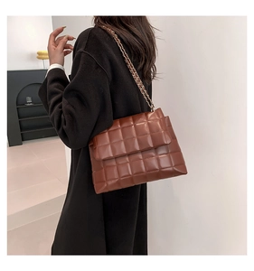 Détail de la surface en cuir PU matelassé marron avec bandoulière chaîne dorée sur le sac