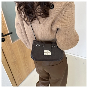Detail of dark brown croc-embossed shoulder bag with silver buckle and chain strap
