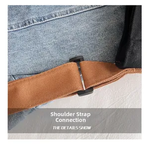 Detail of blue denim fabric bag with sturdy brown canvas strap and black adjustment buckle