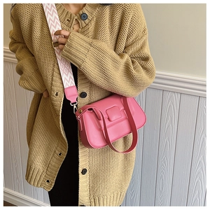 Pink PU leather crossbody bag with wide geometric patterned strap shown on a beige cardigan