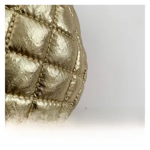 Detailed macro view of golden quilted PU leather fabric with metallic finish on clutch bag
