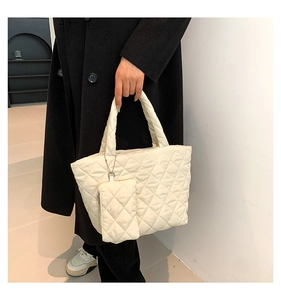 Detail of white quilted tote bag with side coin purse on a black coat background