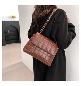 Détail d'un sac à bandoulière matelassé en similicuir marron porté pour montrer sa taille