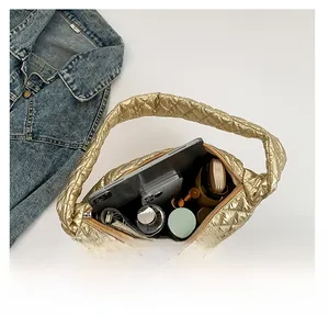 Spacious interior of gold quilted handbag showing storage for tablet, phone and cosmetics