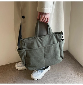 Detailed close-up of a vintage green corduroy handbag featuring multiple front pockets