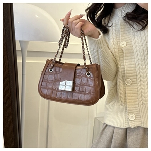Detail of a brown crocodile texture PU handbag with a silver square clasp and chain strap