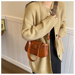 Detailed macro view of caramel PU leather handbag with geometric woven shoulder strap