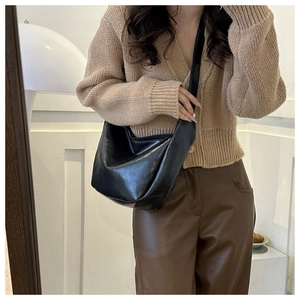 Close-up of stylish black PU hobo bag with wide leather strap worn on shoulder