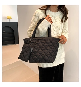 Detail of black quilted nylon tote bag featuring a matching mini pouch charm for winter