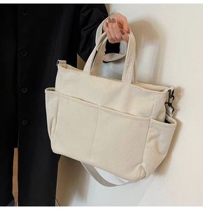 Detail of the off-white corduroy tote bag featuring side storage pockets and fabric strap