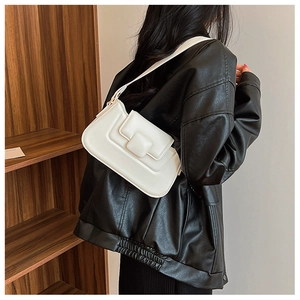 Detailed view of a white minimalist PU leather shoulder bag worn over a black jacket