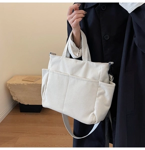 Detailed texture of white corduroy tote bag with front pockets and crossbody strap