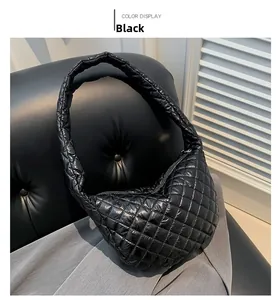 Close-up of black quilted rhombus crossbody bag on sofa with glossy nylon texture