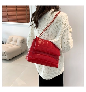 Détail du sac à rabat matelassé rouge en cuir PU avec chaîne élégante sur un mannequin