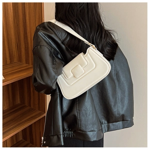 Minimalist beige underarm bag styled on shoulder with a classic square magnetic clasp detail