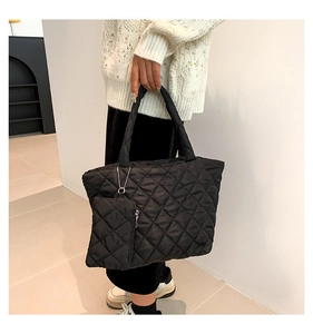 Detailed shot of a black quilted puffer tote bag with matching coin purse and rhombic pattern