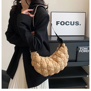 Dettaglio della borsa hobo trapuntata beige con trama a pieghe e tracolla nera