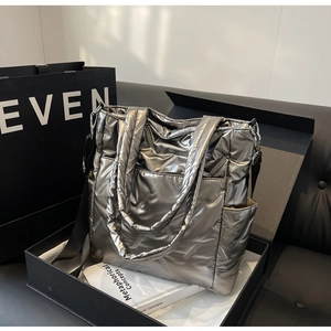 Detailed view of silver metallic quilted tote bag with diamond texture in a black gift box