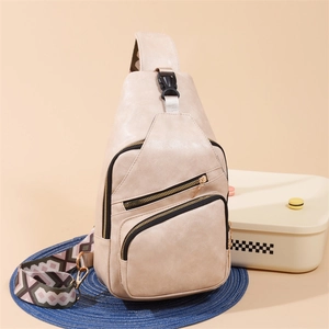 Detail of beige PU leather crossbody bag with three zippers and geometric strap